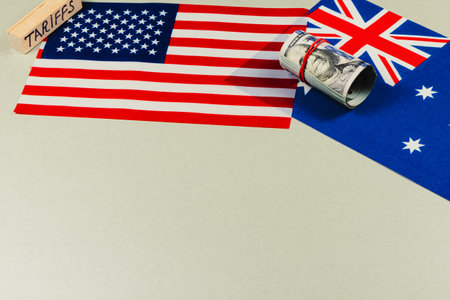 Flags of the USA and Australia are displayed alongside a rolled banknote and a block labeled tariffs, highlighting trade negotiations and economic discussions.の写真素材