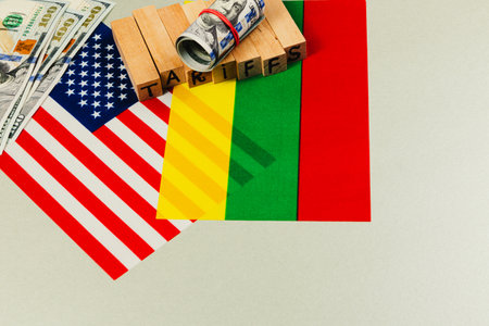 Currency, national flags of the USA and Mali, and letters spelling tariffs symbolize the complex trade relations and negotiations involving taxes and tariffs.の写真素材