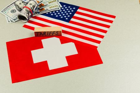 Flags of the USA and Switzerland are displayed alongside cash, emphasizing tensions in trade due to tariffs and political maneuvering.の写真素材