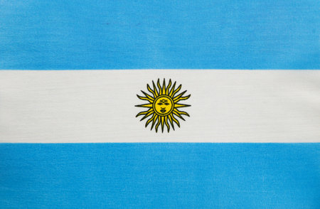 The flag of Argentina features horizontal stripes of light blue and white with a sun emblem in the center. It is prominently displayed on a fabric surface.の写真素材