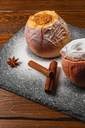 Delicate pastries topped with sugar sit on a dark slate platter beside cinnamon sticks and anise, creating a warm and inviting atmosphere perfect for dessert lovers.の写真素材