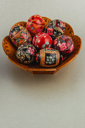 A collection of intricately designed Easter eggs rests in a handmade bowl. The eggs showcase vibrant patterns and colors, perfect for festive decorations.の写真素材