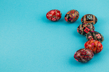Intricately designed decorative eggs are arranged on a blue surface, showcasing vibrant colors and detailed patterns, perfect for holiday celebrations.の写真素材