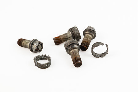 Various broken bolts and a damaged wheel sit on a workbench, showcasing tools and parts needed for repairs. The scene suggests ongoing mechanical work or assembly.の写真素材