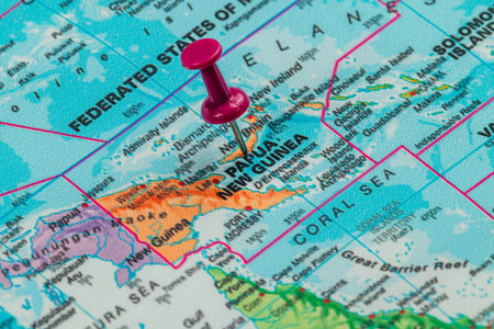 A bright pink pushpin marks the location of Papua New Guinea on a detailed world map, highlighting its geographical significance in the Pacific Ocean region.の写真素材