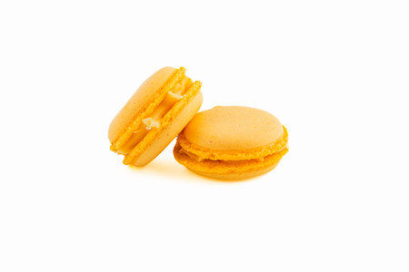 Two bright yellow macarons sit next to each other, showcasing their smooth texture and creamy filling. Ideal for celebrating special occasions or indulging.の写真素材