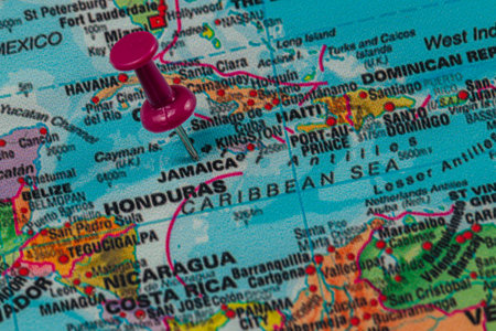 A close-up view of a map displaying Jamaica with a pink pin marking its location in the Caribbean Sea, highlighting surrounding countries and waters.の写真素材