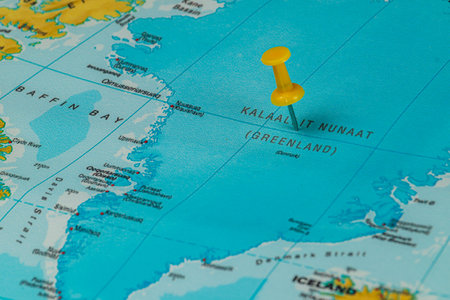 A bright yellow pushpin highlights the Kalaallit Nunaat area on a detailed map of Greenland, surrounded by water and other geographic features of the region.の写真素材