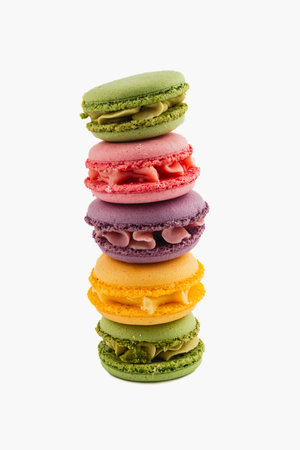 Five vibrant macarons in various flavors are stacked neatly. The bright colors showcase the delightful treats that are perfect for any dessert occasion.の写真素材