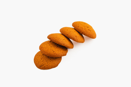 Five freshly baked, round cookies are placed neatly in a row on a clean white surface, showcasing their golden brown color and soft texture.の写真素材