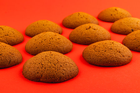 Freshly baked ginger cookies are laid out in an attractive manner on a vibrant red surface, showcasing their brown, smooth surfaces and soft texture.の写真素材