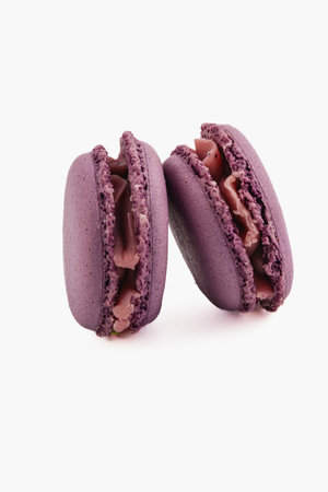 Two vibrant purple macarons are displayed, showcasing a rich chocolate cream filling in the middle, perfect for dessert lovers seeking a sweet treat.の写真素材