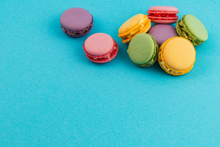 Brightly colored macarons in various flavors are displayed on a vibrant blue surface, showcasing an inviting assortment perfect for dessert lovers and gatherings.の写真素材