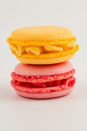 Two delightful macarons are stacked together, featuring a bright yellow shell filled with a creamy center and a pink macaron layered with a delicious filling.の写真素材