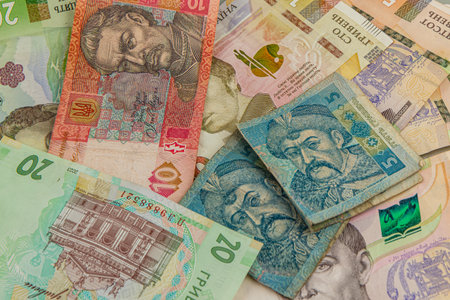 Various denominations of Ukrainian banknotes are spread across a textured surface, showcasing...