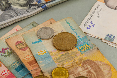 Different denominations of Ukrainian currency are arranged on a table. Banknotes of various colors...
