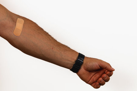 A person's arm is shown with a bandage on the skin after receiving a vaccination, highlighting the...