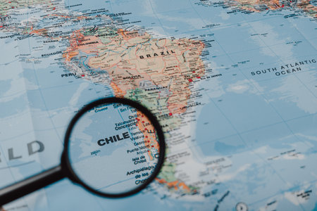 A close-up view of a detailed map of South America highlights Chile. A magnifying glass emphasizes this country's location along the coastline, showing its geography.のeditorial素材