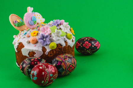 A round cake decorated with icing and flowers sits on a green surface. Nearby are several patterned...