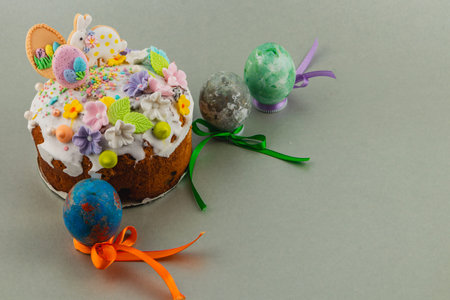 A round cake is topped with icing and colorful decorations. Nearby, there are decorative eggs in...