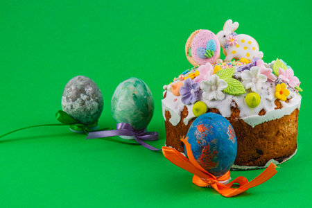 A cake is decorated with icing and flowers. Colorful eggs sit beside the cake, ready for a spring...