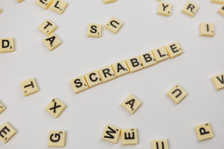 Tiles with letters are spread on a surface. The word Scrabble is formed in the center.