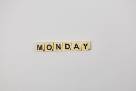 Players enjoy arranging letters to form words. Scrabble tiles spell out MONDAY in a simple game...
