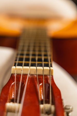 A close view of guitar strings shows details of the fretboard while the body of the guitar appears...