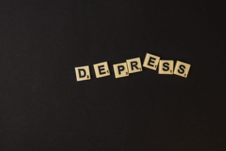 Lviv Ukraine 02.26.26 Scrabble tiles are arranged on a black surface to form the word depress. This setup shows a unique way to celebrate National Scrabble Day with words.のeditorial素材