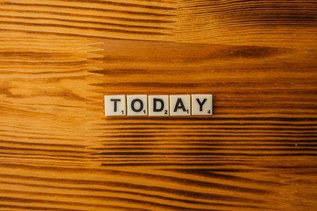 Lviv Ukraine 02.26.26 Scrabble letters spell out the word today on a wooden table. The scene highlights the joy of playing word games. National Scrabble Day encourages fun activities.のeditorial素材