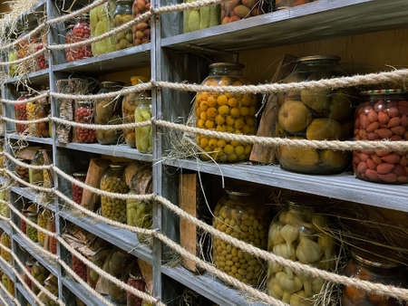 Glass jars with canned food - vegetables and fruits on wooden shelvesの写真素材