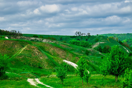 green fields and forests against a blue sky with clouds