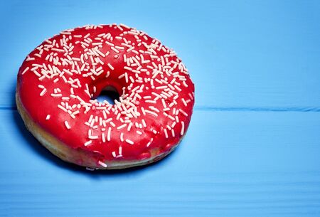 pink glazed donut on a blue backgroundの写真素材