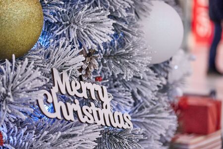 Christmas toys of yellow and white color on a branch of an artificial Christmas tree with the...