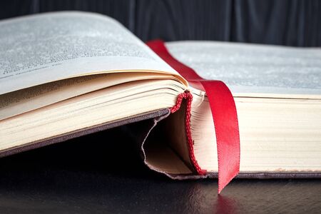 open old book with a red bookmark on a dark background