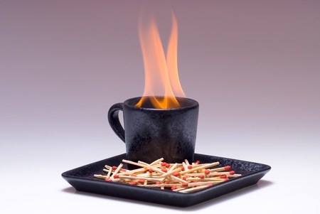 coffee or tea cup of fire with matches on shade background