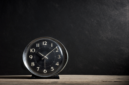 old alarm clock on old wood plank with dark grunge background