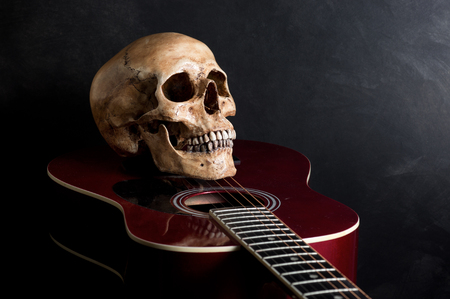 Still life photography, skull with old acoustic guitar on dark backgroundの写真素材