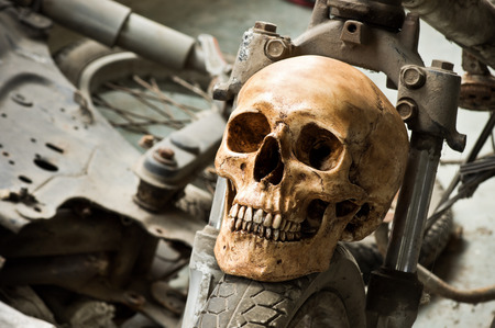 Still life photography, Human skull on front wheel of old motorcycle in junkyard conceptの写真素材