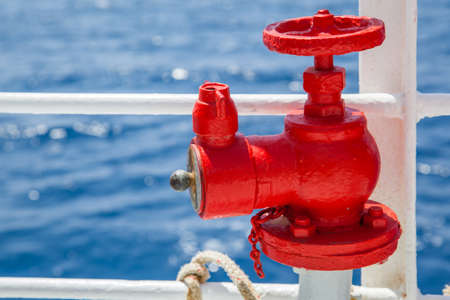 Red fire extinguisher with pipe connector on a boatの写真素材