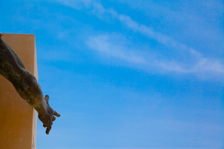 A bronze hand pointing a blue summer skyの写真素材