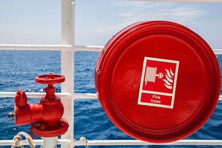 Red fire extinguisher with pipe connector on a boatの写真素材