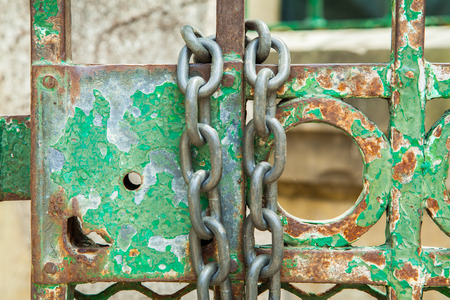 A green rusty lock on an iron door with a chainの写真素材