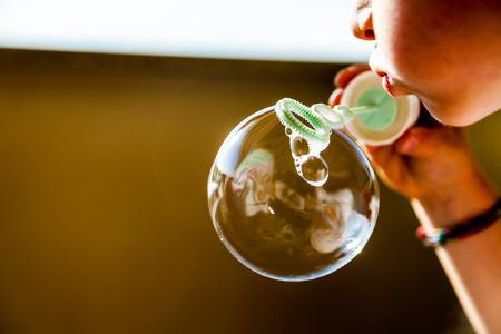 A chlid blowing a soap bobble in summer timeの写真素材
