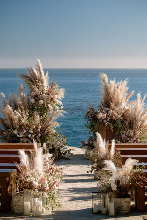 Romantic beach wedding aisle decor with pampas grass and ocean backdrop.の素材