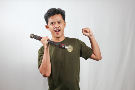 Asian man lifting light barbell while showing off bicep muscles isolated on white background