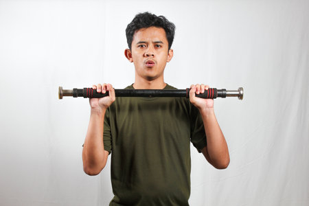 Asian man wearing a green t-shirt lifting a barbell, doing regular arm muscle exercises