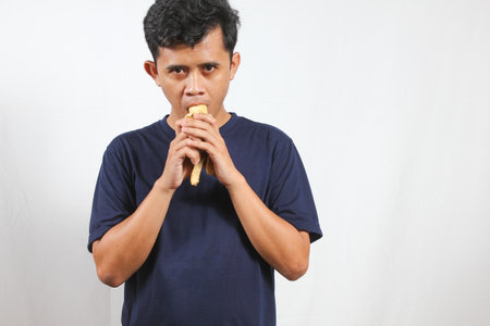 young asian man eating banana isolated white background