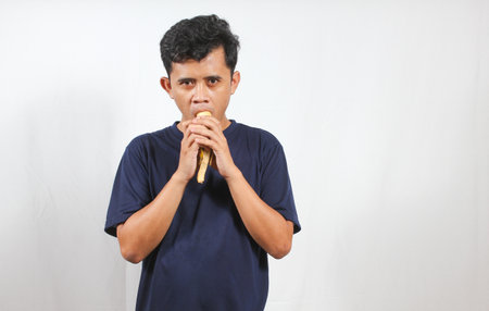 young asian man eating banana isolated white background