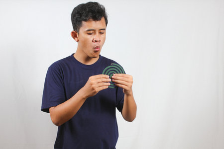 Asian man holding mosquito coil blowing on the flame